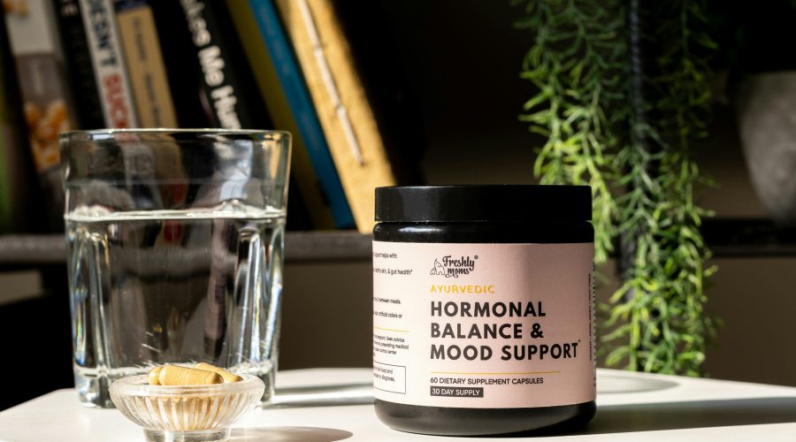 Suplementy stoją na stole wśród nich testosteron sklep internetowy a za nimi półka z książkami